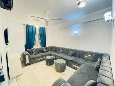 a living room with a large couch and blue curtains at nile shores hotel in Al Aqālitah