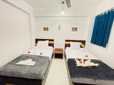 two beds in a room with two swans on them at nile shores hotel in Al Aqālitah