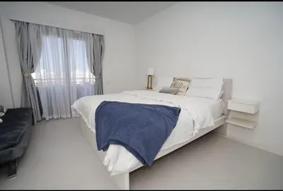 a white bedroom with a bed and a window at Spacious Penthouse in Hurghada