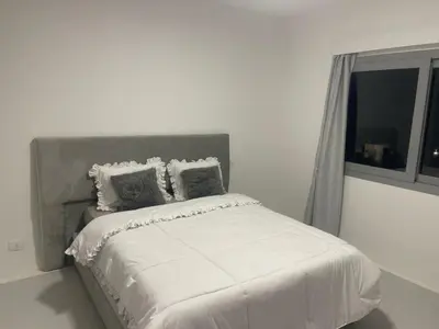 a bed in a white bedroom with a window at Spacious Penthouse in Hurghada