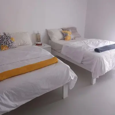 two beds in a room with white walls at Spacious Penthouse in Hurghada