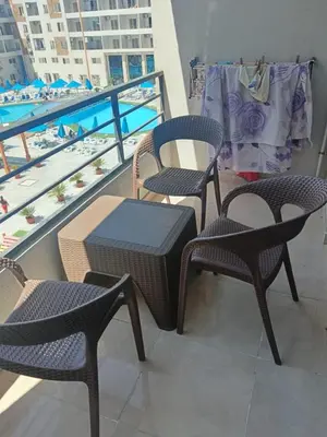 three chairs and a table on a balcony with a pool at استوديو في ذهبية طيبة جولدن الغردقة in Hurghada