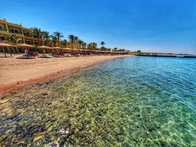 a beach with chairs and umbrellas and the water at Palma Resort in Hurghada