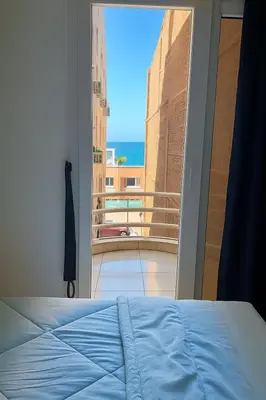 a bedroom with a bed and a view of a balcony at Majestic apartments in Hurghada