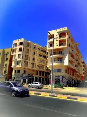 a large apartment building with cars parked in front of it at Majestic apartments in Hurghada