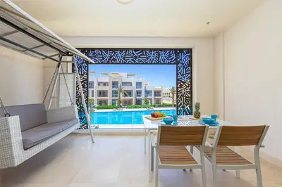 a living room with a table and chairs and a pool at Special apartment with Pool and Seasideview, El Gouna in Hurghada