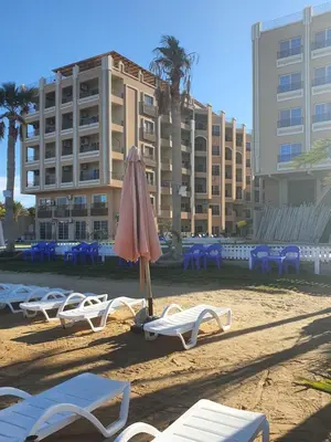 a beach with chairs and an umbrella and a hotel at جوليانا بيتش ريزورت in Hurghada