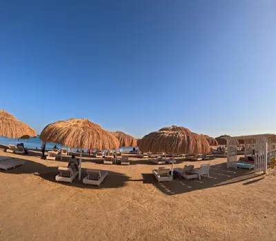 a group of chairs and straw umbrellas on a beach at Avenuo apartment in Hurghada