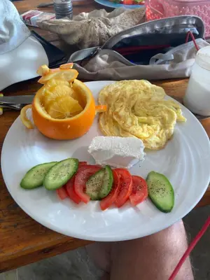 a plate with an omelet and an orange and vegetables at Kody doll in Jazīrat Suhayl
