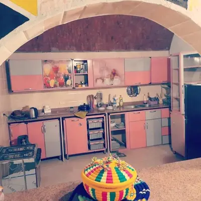 a kitchen with pink and white cabinets and a basket at Kody doll in Jazīrat Suhayl