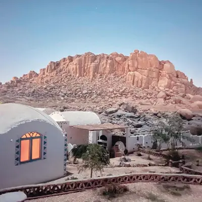 a house in the desert with a mountain in the background at Kody doll in Jazīrat Suhayl