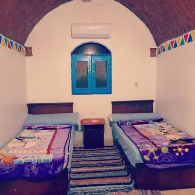 two beds in a room with a window at Kody doll in Jazīrat Suhayl