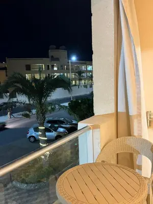 a table and chair on a balcony at night at كمباوند فلورينزا خمسين وسط الغردقه in Hurghada
