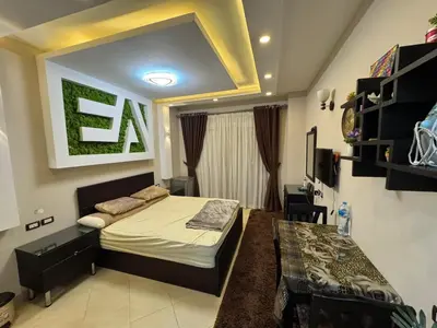 a bedroom with a bed and a table in it at كمباوند فلورينزا خمسين وسط الغردقه in Hurghada