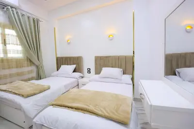 two beds in a room with a mirror at Jeanie's House in Al Karnak