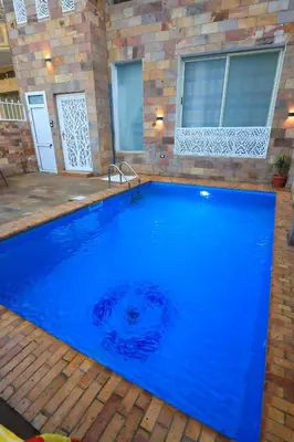 a large blue swimming pool in a backyard at Jeanie's House in Al Karnak