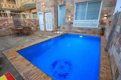 a large blue swimming pool with a table and chairs at Jeanie's House in Al Karnak