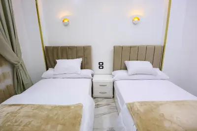 two beds in a small room with the number six at Jeanie's House in Al Karnak