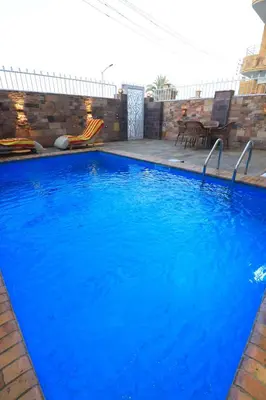 a large pool with blue water in a backyard at Jeanie's House in Al Karnak