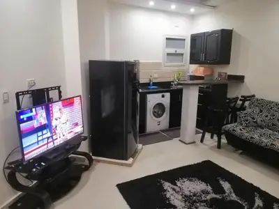 a living room with a television and a kitchen at كذابلانكا بيتش in Hurghada