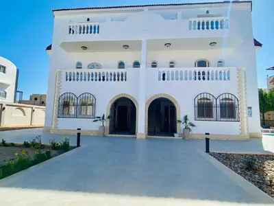 a large white building with two entrances at Magawish Hurghada Apartement 1 in Hurghada