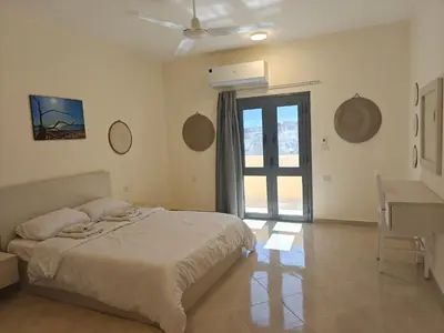 a bedroom with a bed and a desk and a window at Bayt Hassan S19 - Super spacious roof top One Bedroom apartment in Hurghada