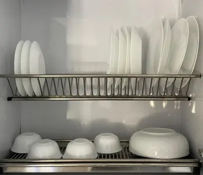 a shelf with white plates and bowls in a kitchen at Bayt Hassan A3 - 2 bedrooms European style Apartment in Hurghada