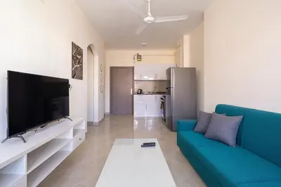 a living room with a blue couch and a flat screen tv at Bayt Hassan A3 - 2 bedrooms European style Apartment in Hurghada