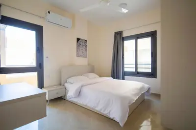 a bedroom with a white bed and two windows at Bayt Hassan A11 - 2 bedrooms spacious appartment in Hurghada