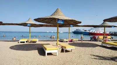 a beach with umbrellas and people in the water at touristic centre Andalusia in Hurghada