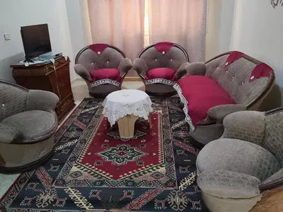 a living room with chairs and a table and a rug at Hamza home in Quseir