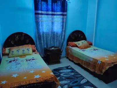 two beds in a room with blue walls at Hamza home in Quseir