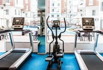 a gym with two exercise machines in front of a window at Cozy one bedroom apartment in AquaPalms resort in Hurghada