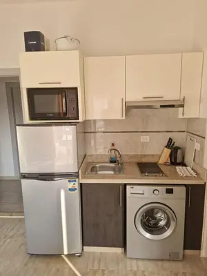 a kitchen with a refrigerator and a washing machine at Cozy one bedroom apartment in AquaPalms resort in Hurghada