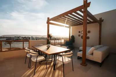 a balcony with a table and chairs and a couch at Shedwan Sky Loft Rooftop Escape with Pool View in Hurghada