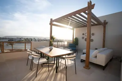 a balcony with a table and chairs and a couch at Shedwan Sky Loft Rooftop Escape with Pool View in Hurghada