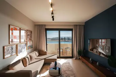 a living room with a couch and a large window at Shedwan Sky Loft Rooftop Escape with Pool View in Hurghada
