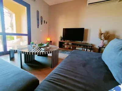 a living room with a couch and a table and a tv at Cozy Lagoon Escpae-1Bdr Retreat in Hurghada