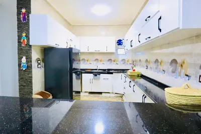 a large kitchen with white cabinets and a black refrigerator at Memnon House in Al Karnak