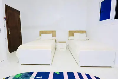 two beds in a room with white walls at Memnon House in Al Karnak