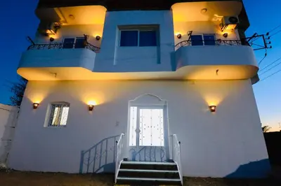 a white house with a door and stairs at Memnon House in Al Karnak