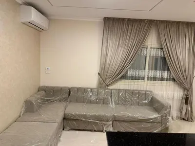 a living room with a leather couch in front of a window at Helal Apartment in Hurghada