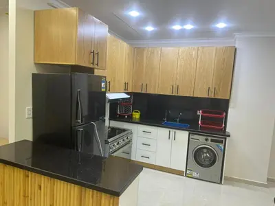 a kitchen with wooden cabinets and a washer and dryer at Helal Apartment in Hurghada
