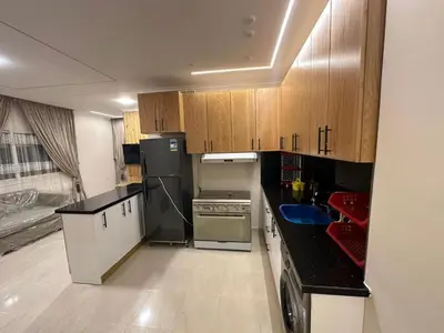 a kitchen with wooden cabinets and a black refrigerator at Helal Apartment in Hurghada