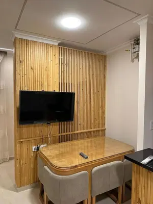 a room with a table with chairs and a television on a wall at Helal Apartment in Hurghada