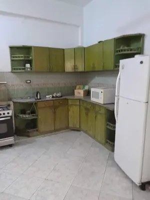 a kitchen with wooden cabinets and a white refrigerator at Nube's dream house in Luxor