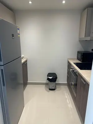 a small kitchen with a refrigerator and a trash can at G cribs cozy 1bd apartment in El Gouna