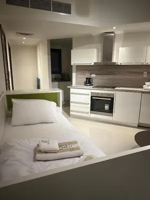 a white bedroom with a bed and a kitchen at G cribs cozy studio in El Gouna