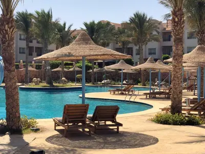 a resort with a pool with chairs and umbrellas at Sunset Pearl Sahl Hashesh in Hurghada