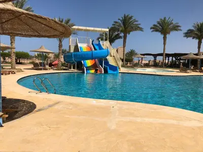 a large swimming pool with a water slide in a resort at Sunset Pearl Sahl Hashesh in Hurghada
